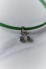 Gargantilla con cordón rojo y dije de cerezas rojas con detalles dorados y hojas verdes.