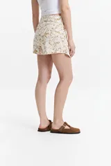 Minifalda estampada con diseño marmolado en tonos beige y gris. Presenta un corte pareo con nudo frontal.