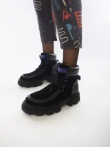 Borceguíes de cuero color negro con detalles en azul, diseño de caña corta y tobillo acolchado. Cuentan con suela de plataforma acanalada, cierre de cordones y trabilla trasera para facilitar el calce.