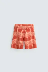 Short de baño color ladrillo con estampado de líneas curvas en color salmón. Tiene cintura elástica ajustable con cordón, bolsillos laterales y trasero.