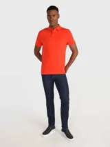 Chomba naranja de Tommy Hilfiger, corte regular, con cuello tipo chomba, cartera de dos botones, logo de la marca bordado en el pecho y mangas cortas.