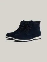 Botines Tommy Hilfiger de hombre, color azul marino, confeccionados en ante con interior de poliéster y suela de goma. Presentan cordones, logo Hilfiger en el tobillo y detalle distintivo en el talón.