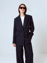 Blazer azul marino con rayas verticales blancas, de corte clásico, con solapas de muesca, cierre frontal con dos botones, bolsillos con solapa y abertura en la espalda.