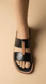 Sandalia con dos tiras de cuero negro y una tira central de cuero marrón.