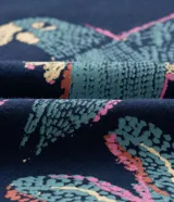 Remera cropped de algodón azul marino, con cuello redondo, mangas cortas y estampa delantera de guacamayas y cocoteros.