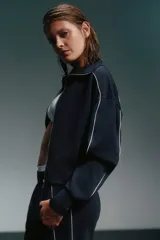 Conjunto deportivo azul marino con detalles de ribete blanco. Incluye una campera corta con cierre y un pantalón de corte recto.