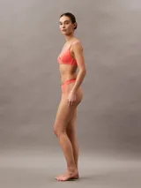 Conjunto de lencería color coral, compuesto por un corpiño triangular sin aro y una bombacha tipo colaless con cintura elástica.