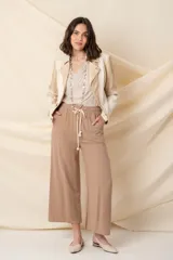 Chaqueta corta cruzada de cuero vegano color marfil, combinada con tela rayada color oro, con cierres metálicos y tachas doradas.