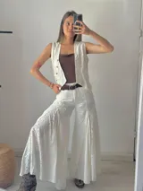Pantalón blanco de corte palazzo con aplicaciones de encaje floral en los laterales.