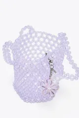 Bolso mini saca cilíndrica con cuerpo de cuentas transparentes y bolsita interior de tela satinada color lila con cierre fruncido. Incluye charm extraíble con forma de cubo.
