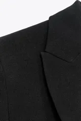 Blazer negra de corte clásico, con cuello solapa, manga larga, bolsillos frontales con solapa y cierre frontal con un botón.