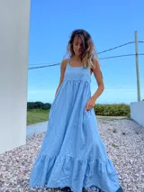 Maxi vestido celeste de jean con breteles regulables y bolsillos laterales.