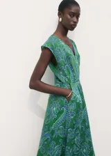 Vestido midi evasé verde con estampado paisley en tonos azules. Tiene cuello en V, sin mangas y dos bolsillos laterales.