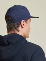Gorro de gabardina color crudo con visera negra y logo bordado en el frente.