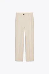 Pantalón color beige confeccionado con lino, de tiro alto, pernera recta, bolsillos delanteros y falsos bolsillos de vivo en la espalda. Cierre frontal con cremallera y botón.
