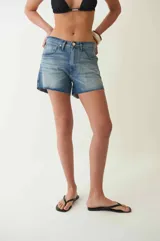 Short de jean celeste de tiro bajo con fit holgado, cuatro bolsillos, presillas para cinturón, cierre con cremallera y botón metálico.