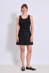 Minifalda negra con textura y volados en la cintura.