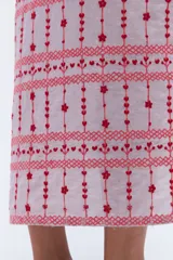 Vestido largo de lino en color celeste, con cuello camisero, manga corta y cierre frontal con botones. Presenta bordados decorativos en contraste en la pechera y en el ruedo.