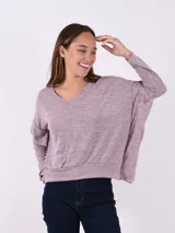 Buzo de tejido melange gris claro, con cuello en V y manga larga. El calce es holgado y el ruedo ajustado con elástico.