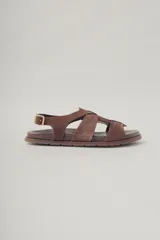 Sandalias planas de cuero color marrón con tiras cruzadas y hebilla lateral.