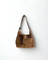 Cartera marrón de cuero con flecos y doble asa circular metálica.