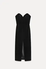 Vestido midi negro de terciopelo, palabra de honor con escote corazón y hombros descubiertos. Tiene detalle de elástico tipo nido de abeja en la espalda y abertura en el bajo.