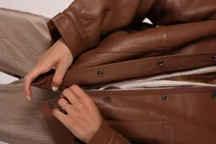 Campera bomber negra de cuero sintético con cuello de corderito blanco, cierre frontal con cremallera y botones a presión, bolsillos laterales y puños y cintura elastizados.