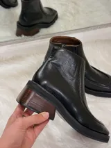 Botas de cuero negras con punta cuadrada, taco bajo de madera y cierre lateral.