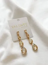 Aros colgantes dorados con tres cristales facetados color champagne en forma de lágrima.