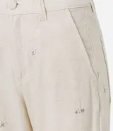 Pantalón de mujer color blanco roto, de corte recto y tiro alto, con un largo cropped y ligero ensanchamiento en el bajo. Presenta detalles bordados florales sutiles en la tela y bolsillos.