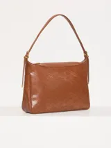 Cartera hobo color marrón confeccionada en cuero vacuno flor, con acceso mediante cierre superior y correa regulable con hebillas metálicas.