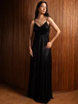 Vestido largo metalizado color negro, con tirantes finos, escote en V, falda plisada y espalda abierta con nudo.