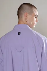 Camisa celeste de manga corta con doble bolsillo y ojal delantero con solapa en uno de ellos. Tiene calce oversize y está realizada en tejido plano suave al tacto.