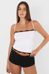 Top blanco de microfibra con corte slim fit y breteles regulables. Detalles de puntilla negra en terminaciones.