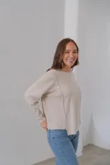 Sweater beige de punto, corte recto, cuello redondo y detalle de botones en el lateral.