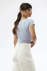 Crop top celeste de tejido de punto acanalado, con escote en V y detalle de abertura circular en el centro.