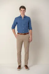Pantalón de vestir color gris claro, de corte slim fit, con bolsillos laterales y traseros. Se ajusta a la cintura con cinturón de cuero marrón.