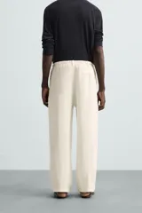 Pantalón de lino color crudo, de corte ancho, con cintura elástica ajustable con cordón, bolsillos laterales y trasero.