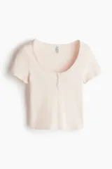 Remera corta de punto acanalado color rosa pálido con rayas horizontales y escote redondo amplio con tapeta de botones.