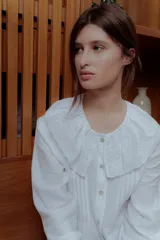 Camisa blanca de lino con cuello babero de broderie y mangas largas.
