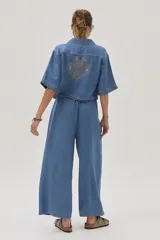 Blusa celeste de denim con cuello camisero, mangas cortas y cierre frontal con botones.