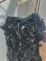 Vestido corto negro con lentejuelas de distintos tamaños, tirantes finos elastizados y cierre en la espalda.