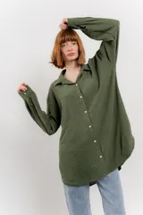 Camisa verde militar con estampado de lunares blancos, de corte oversize, con cuello camisero, cierre frontal con botones y bolsillo en el pecho.