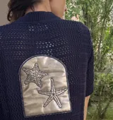 Saco de punto calado azul marino con aplique de cuero plateado bordado con dos estrellas de mar en la espalda.