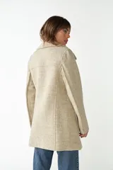 Abrigo de lana color beige con cuello solapa y manga larga. Cierre frontal cruzado doble con botones dorados. Bolsillos delanteros plaqué y forro al tono. Tela 100% lana fina sin teñir, diseñada exclusivamente por Don Baez. Hecho 100% en Uruguay.