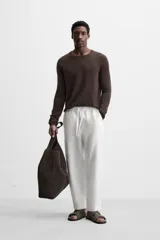 Pantalón de lino color marrón oscuro, de corte recto y relaxed fit. Tiene cintura elástica ajustable con cordón, bolsillos frontales y traseros de parche.