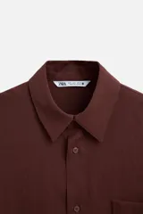 Camisa color borgoña de corte relajado, confeccionada en tejido con mezcla de viscosa. Tiene cuello solapa, manga larga con puños abotonados, bolsillo de parche en el pecho y cierre frontal con botones.