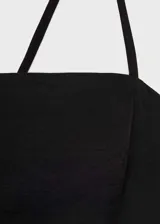 Vestido corto negro con tirantes finos cruzados en la espalda, diseño evasé y cuello escotado.