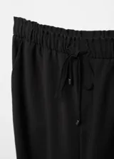 Pantalón recto negro de tejido fluido con cintura elástica y lazo ajustable.