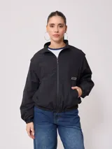 Campera negra tipo rompevientos de nylon con cierre frontal y bolsillos laterales.
